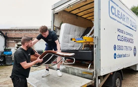 two men loading a chair onto a van following a flat clearance