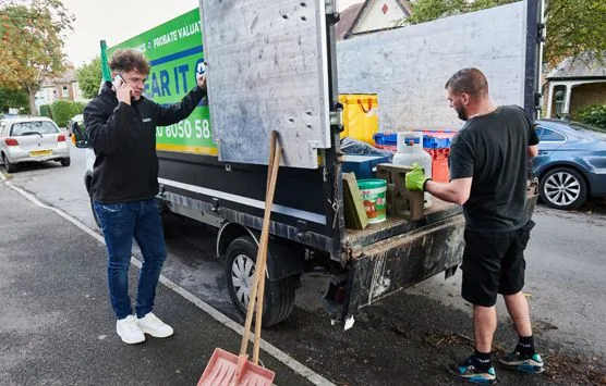 Two men outside a van clearing scrap metal