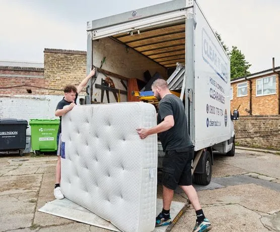 two men loading the mattress into a van, doing a house clearance in Norbury