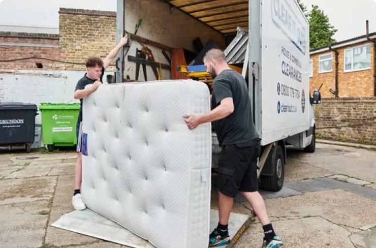 Two men carrying a mattress as part of a house clearance