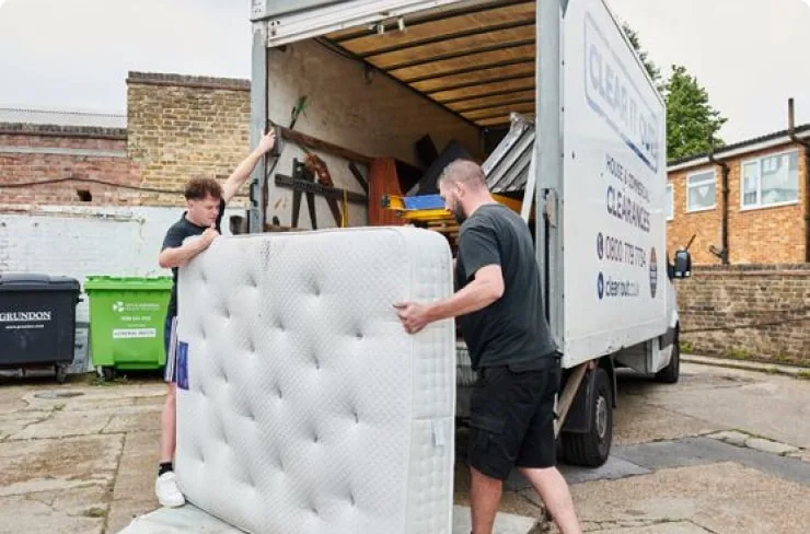 A photo of house clearance specialists removing a mattress and loading it into a van