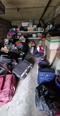 A very full looking garage filled with old suitcases and boxes that requires removing using a clearance service