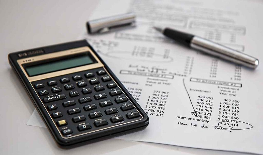 An image of a calculator on top of a finance document with a pen laid on top with it's lid off