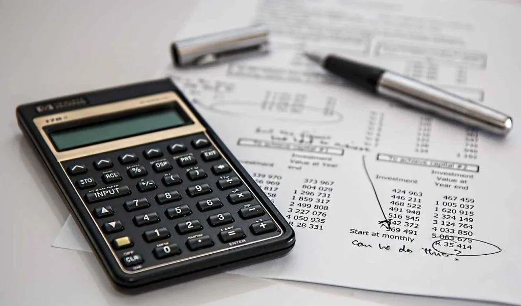 An image of a calculator on top of a finance document with a pen laid on top with it's lid off